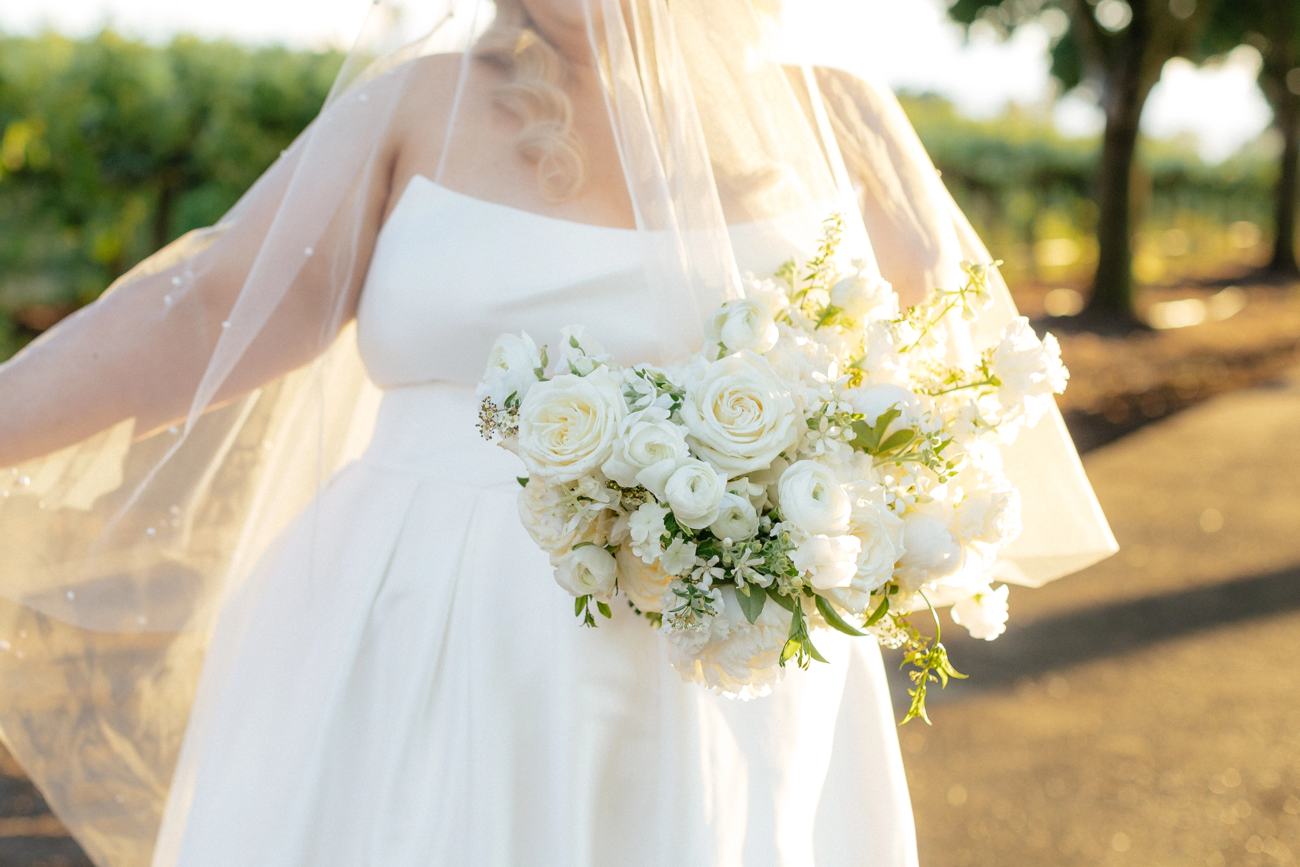 Bride wearing Aspen by Sottero and Midgley with her wedding veil and bouquet outside.